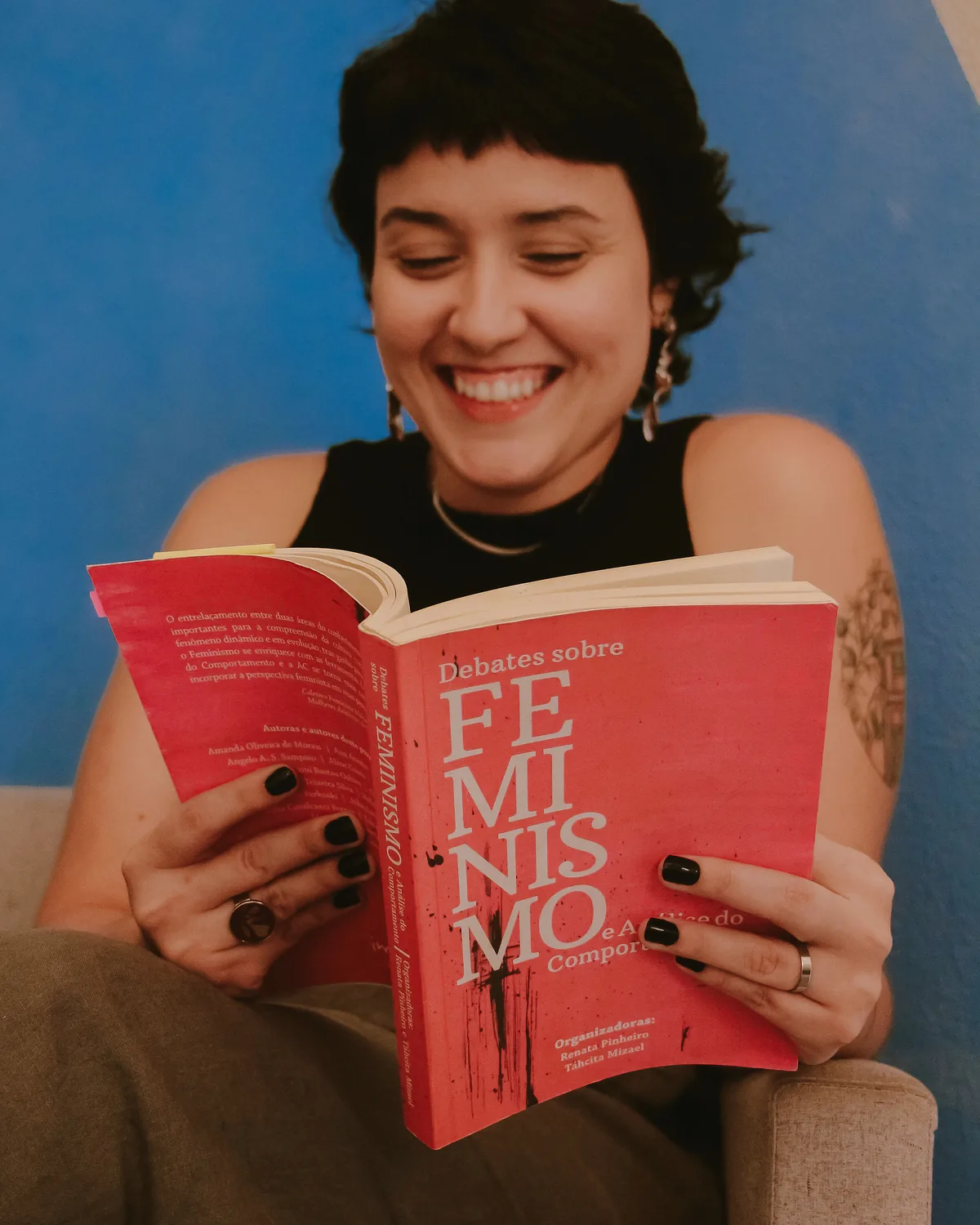 Veri rindo enquanto lê o livro Debates sobre Feminismo e Análise do Comportamento
